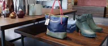 MODEGESCHÄFT, IN DEM EINE Handtasche mit Preisetikett und Schuhe auf Einem Tisch Stehen.