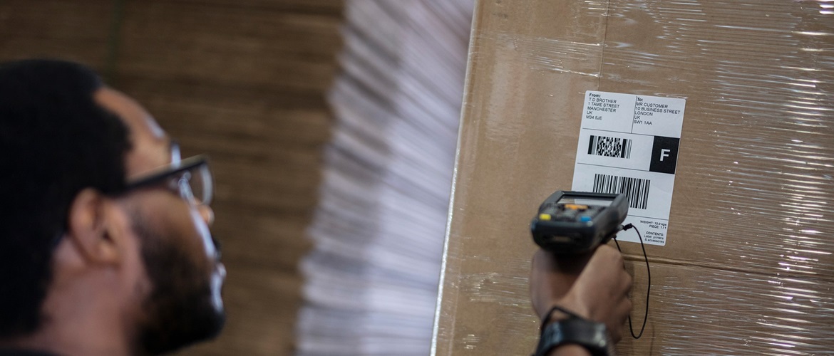 Mann scannt versandetikett auf verpacktem karton