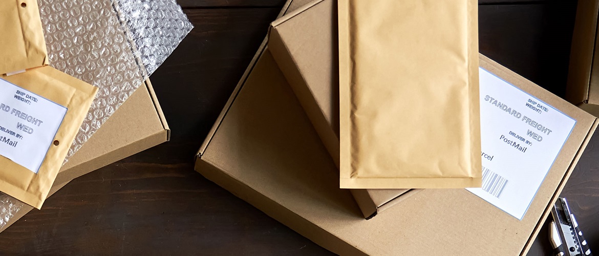 Auf einem Tisch liegen Pakete und Briefe, die mit Etiketten zum Paket beschriften versehen sind