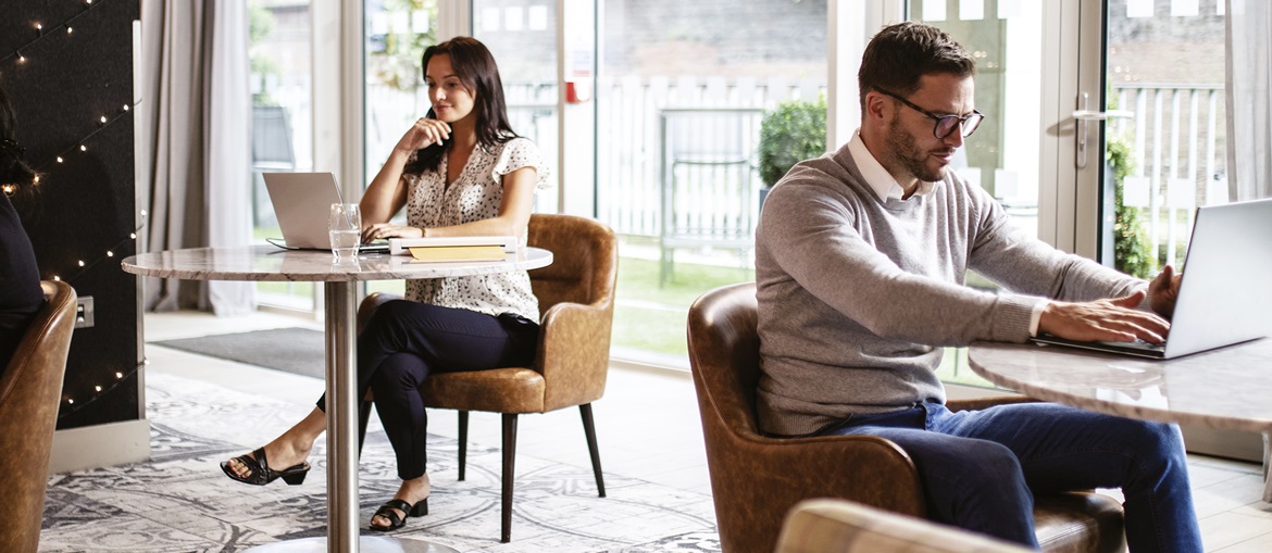 Mensch am Tisch in Einem Bistro am Tisch mit Computer