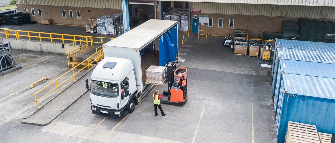Transport und Logistik, Luftaufnahme der Laterampe, Weißer und Blauer van, OrangeFarbener Gabelstapler, Person mit Warnschutzjacke