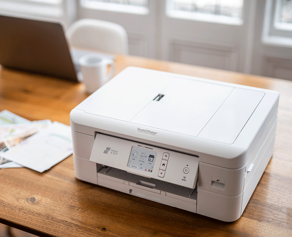 Multifunktionsdrucker DCP-J1800W von Brother auf einem Tisch. Ein Laptop steht im Hintergrund.