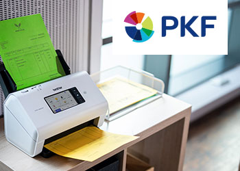 Ein Scanner steht auf einem Tisch mit Druckerzeugnissen im Vorlageneinzug und in der Auslage.