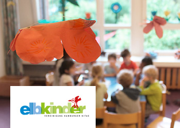 Bastelarbeiten von Kindern im Vordergrund, spielende Kindergruppe im Hintergrund