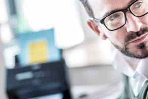 MANN IM BÜRO mit Scanner im Hintergrund