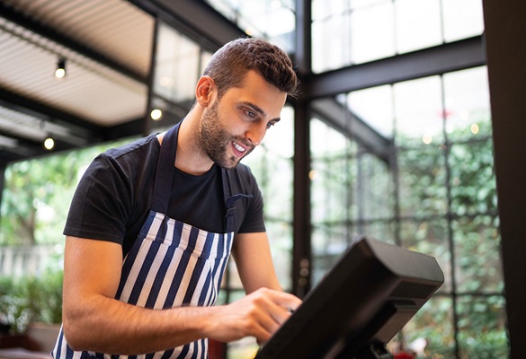 Kellner in Schwarzem T-Shirt und Gestreifer Schürze Benuttt Die Kasse mit Touchscreen