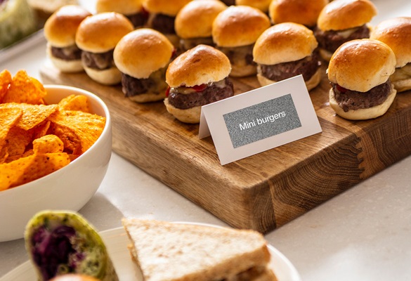Teller mit Sandwiches, Mini-Burger auf Tisch mit Buffetschilder