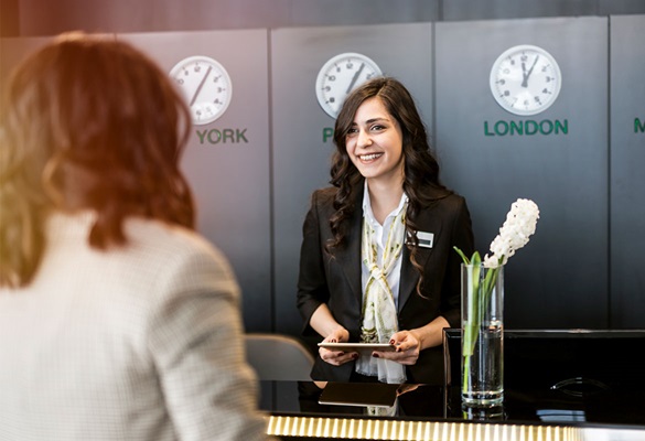 Hotelgast an der Rezeption mit Concierge, Uhren, Computer, Vase