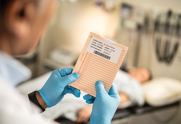 Arzt mit Blauen Handschuhen hält Patientenakte mit Patientendaten auf ETIKETT, Patienten, Liegt mit medizinischer Ausrüstung im Boden