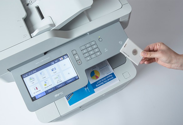 Die Hand einer Person Hält ein NFC-Karte gegen einen Brother-MultifunktionsDrucker mit Großem Bildschirm