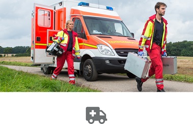Rettungssanitäter mit Ausrüüstung auf Einem Feldweg mit RTW