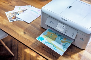 DCP-J1800DW in Home-Office-Umgebung, druckt Dinosaurier-Grußkarte aus