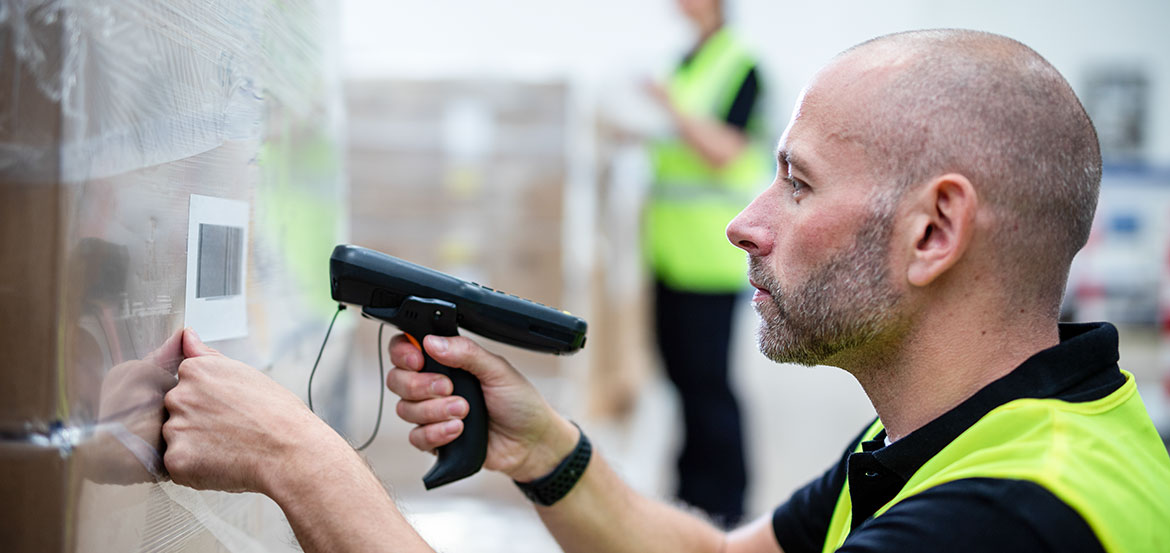 Mann in Warnweste Scannt Barcode-Etikett