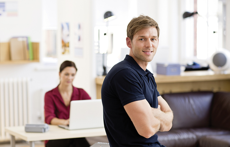 Mann im Büro im Hintergrund Frau am Schreibtisch