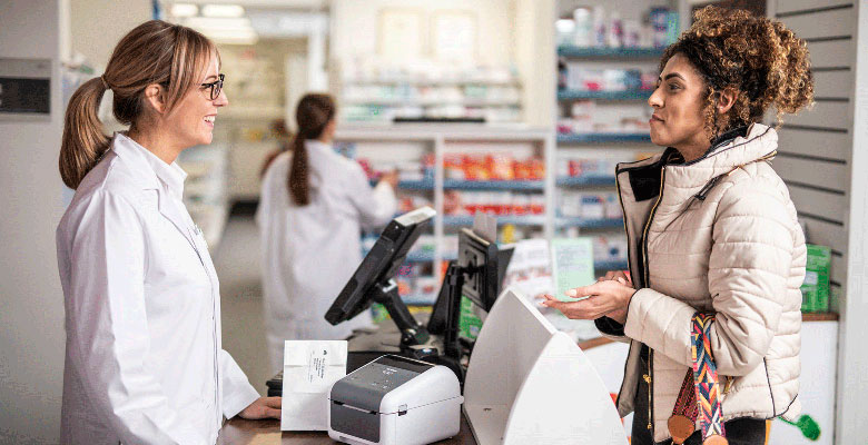 Apotheker, der mit dem Kunden über den Zähler mit Brother TD Desktopdrucker spricht