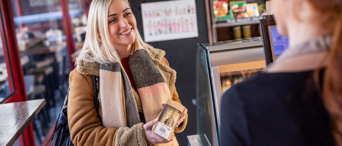 Frau kauft im Supermarkt ein Sandwich mit Barcode-Etikett