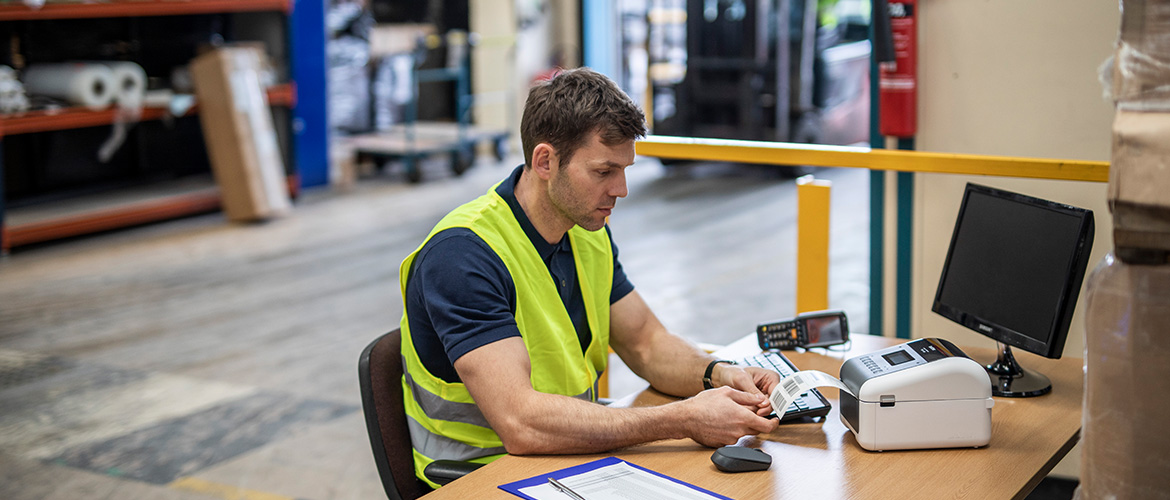 Arbeiter in Lagerhalle druckt Versandetikett.