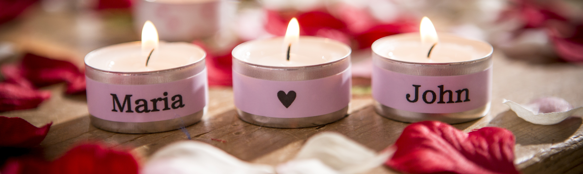 Lit candles personalised with names on a pink label using a Brother P-touch label and ribbon printer